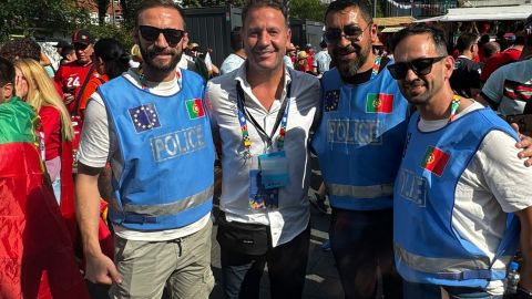 Three police officers from Portugal stand in a group of fans