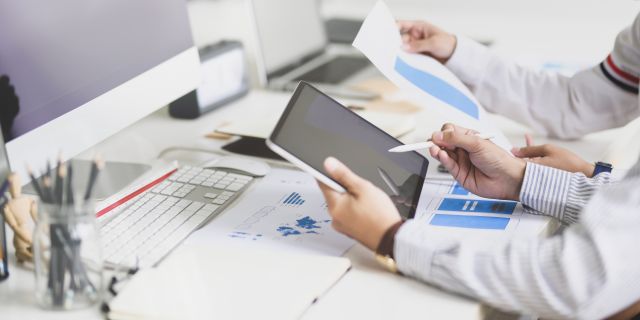 Zwei Männer am Schreibtisch schauen auf ein Tablet