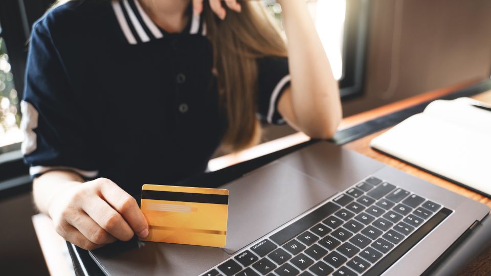 Frau sitzt mit Kreditkarte vor dem Computer